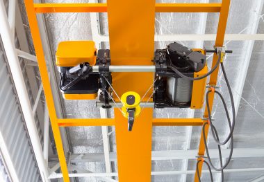 Overhead crane and hook inside factory building for lifting work.